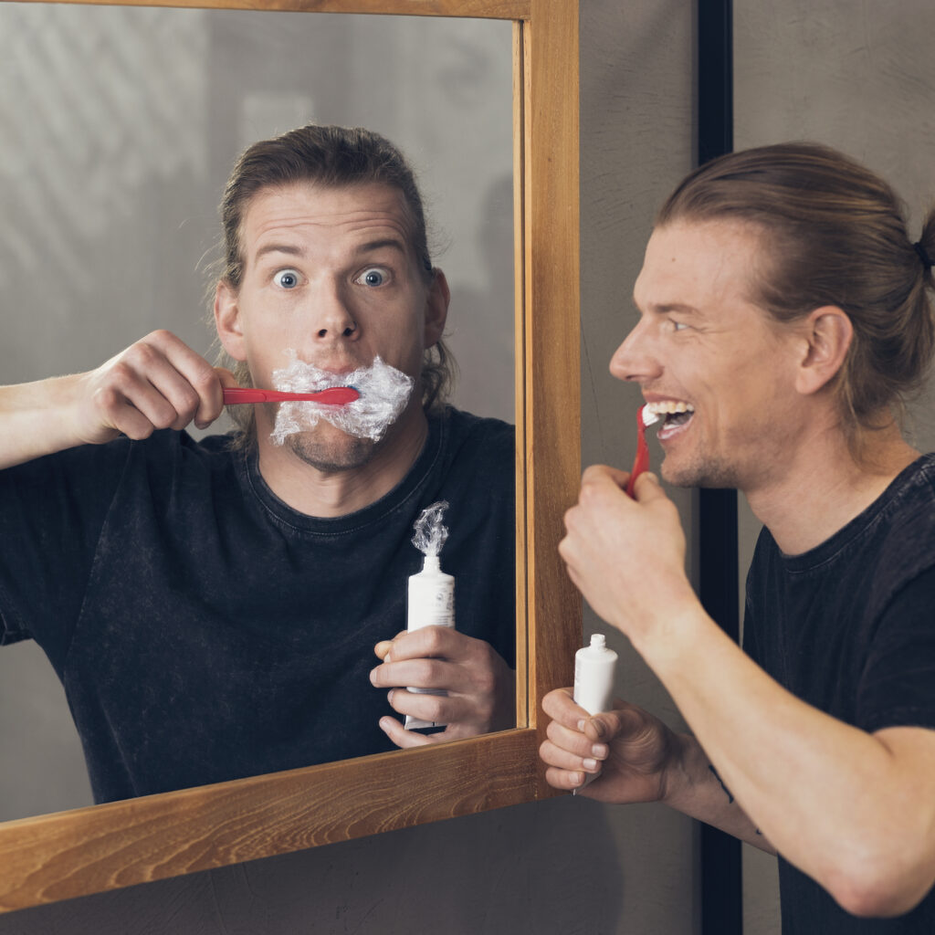 young man brushing his teeth with a plastic toothpaste